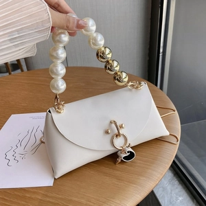 Detail of white leather handbag with pearl beaded handle and golden ring lock
