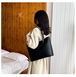 Close-up of black leather tote bag showing smooth matte texture and sleek shoulder straps