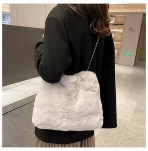 Detail of soft light gray faux fur crossbody bag with elegant golden chain strap