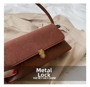 Detailed close-up of golden metal clasp on a vintage brown leather underarm handbag