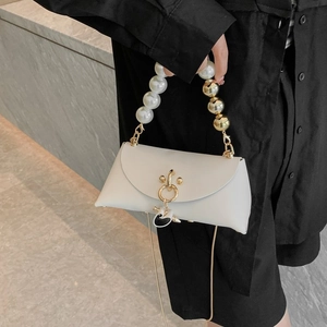 White minimalist handbag with pearl handle and golden metal ring lock closure