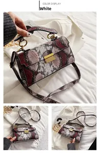 Close-up of snakeskin pattern leather bag with gold hardware and rotating clasp detail