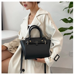 Litchi pattern black leather handbag styled with beige trench coat for a casual look