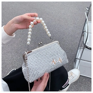 Detail of silver evening bag with pearl handle, diamond studs, and butterfly accents