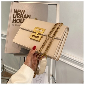 Macro view of cream crossbody bag featuring matte gold geometric lock and chain detail
