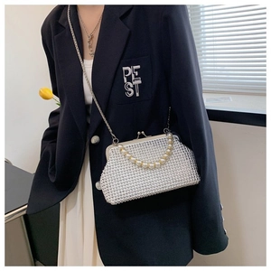 Detail of white rhinestone shell bag with pearl handle and metal chain strap on blazer