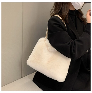 Detail of white faux fur crossbody bag with elegant gold metal chain shoulder strap