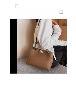 Dettaglio laterale della borsa in pelle marrone con grana litchi e fibbia dorata