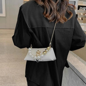 Detail of white leather shoulder bag with decorative large pearls and gold beads on strap