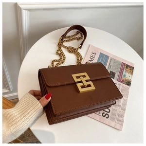 Close-up of brown leather bag with geometric gold lock and chunky chain strap