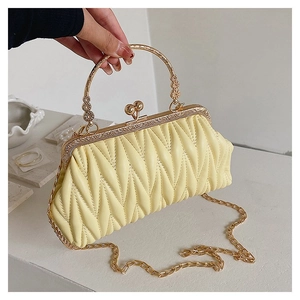 Detail of light yellow quilted matelassé clutch bag with golden ring handle and chain