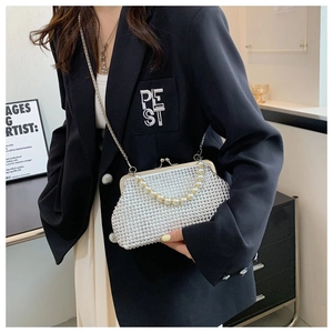 Crossbody view of an elegant pearl and rhinestone shell evening bag with metal chain