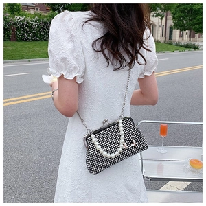 Detail of black pearl evening bag with butterfly clasp and crossbody chain on a model