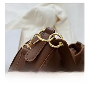 Detailed macro view of the shiny golden hardware hook on the brown faux leather bag
