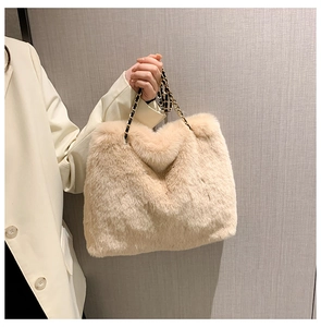 Close-up of beige faux fur tote bag featuring a gold metal chain and leather strap