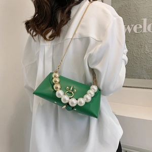 Detail of green faux leather crossbody bag featuring large pearl and gold bead handle