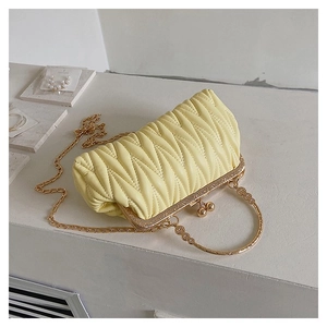 Detail of light yellow quilted purse with gold metal handle and luxury V-pattern texture