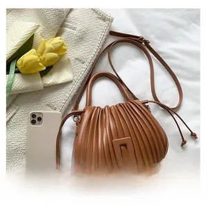 Close-up of brown pleated bucket bag with square buckle detail and adjustable strap