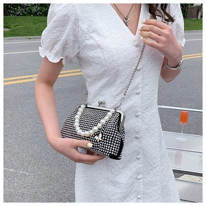Detail of black vintage rhinestone clutch with pearl handle and metal crossbody chain