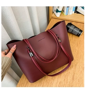 Close-up of deep red tote bag with white stitching details and embossed text on leather