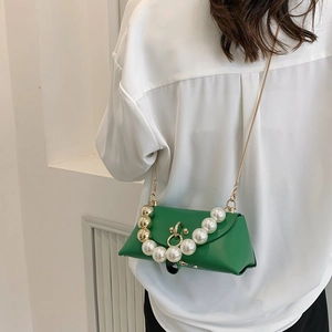 Detail of green leather handbag with oversized pearls handle and gold chain strap