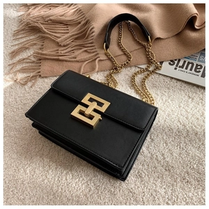 Close-up of elegant black leather handbag with gold geometric buckle and chain strap