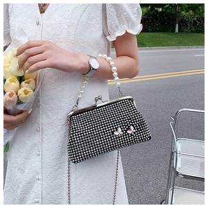 Detail of rhinestone clutch bag featuring white butterflies and elegant pearl handle
