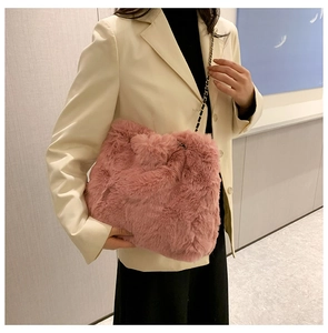 Close-up of pink faux fur cloud bag with gold chain strap on a female model
