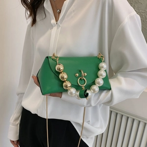 Fashionable green handbag with pearl and gold ball accents shown on a model