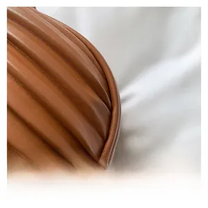 Close-up of caramel brown leather handbag with pleated texture and precise stitching