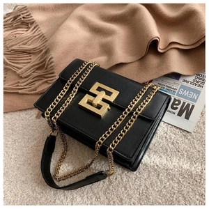 Close-up of black litchi grain leather bag with gold chain and large geometric clasp
