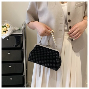 Close-up of elegant black beaded clutch bag with pearl handle and silver metal frame