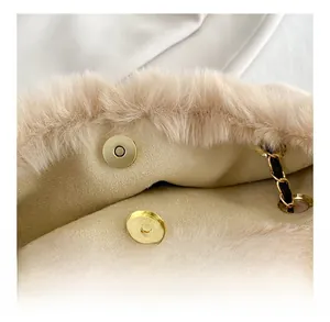 Detail of beige plush handbag featuring a gold magnetic closure and metal chain strap