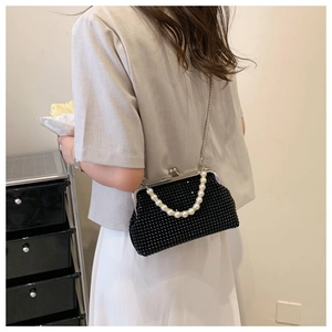 Detail of a black beaded evening bag with pearl handle and metal chain for versatile wear