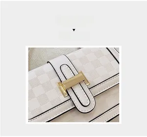 Detail of white checkered leather bag with gold H-shaped clasp and black edge oil finish