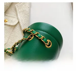 Détail du sac en cuir vert avec bandoulière chaîne dorée et œillets métalliques