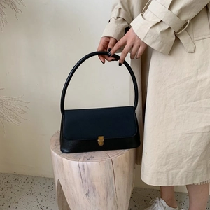 Detail of a vintage black leather handbag featuring a sleek gold metal buckle and round handle