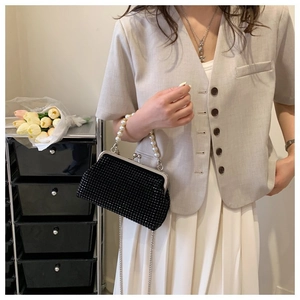 Detail of elegant black beaded clutch bag with large pearl handle and silver chain strap
