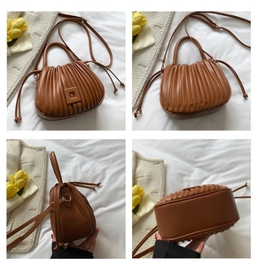 Close-up of a brown pleated PU leather bucket bag with square buckle and drawstrings