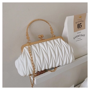 Detail of white matelasse shoulder bag with heart lock and golden chain strap