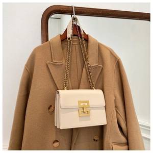 Detail of cream crossbody bag with golden geometric lock and chain strap on wool coat