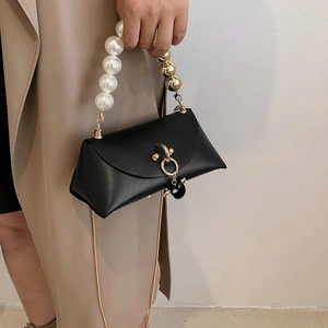 Detail of elegant black leather handbag featuring pearl handle and gold chain strap