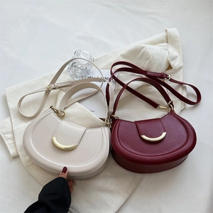 Flat lay of cream and wine red saddle bags with crescent metal buckles on fabric