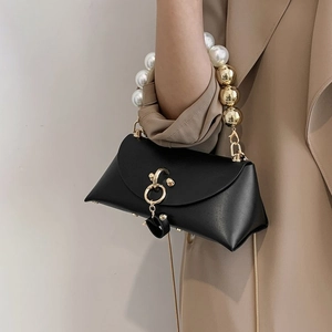 Detail of elegant black matte leather bag with white pearl and gold bead handle