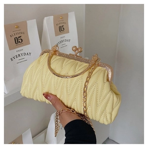 Close-up of pale yellow quilted crossbody bag with gold-tone metal frame clasp closure