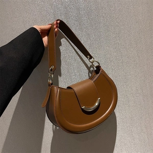 Detailed view of a brown leather saddle bag with gold crescent hardware buckle and strap