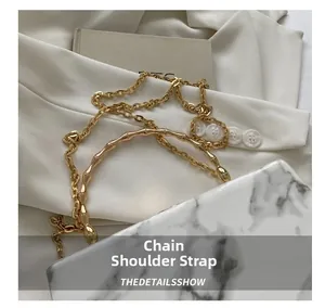 Detail of golden metal chain shoulder strap with bamboo texture handle and marble accent