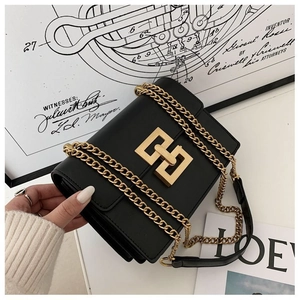 Detail shot of black leather handbag featuring a gold geometric buckle and chain strap