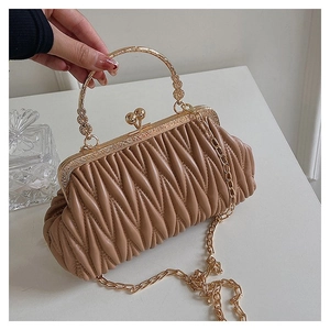 Close-up of khaki pleated bag with ornate gold metal handle and vintage frame closure