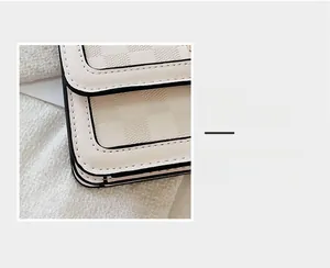 Detailed close-up of cream checkered crossbody bag featuring high-quality stitching and black edges